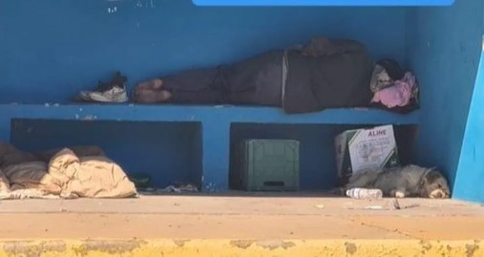 Personas en situación de calle pasan la noche en una garita de colectivos en Roca 