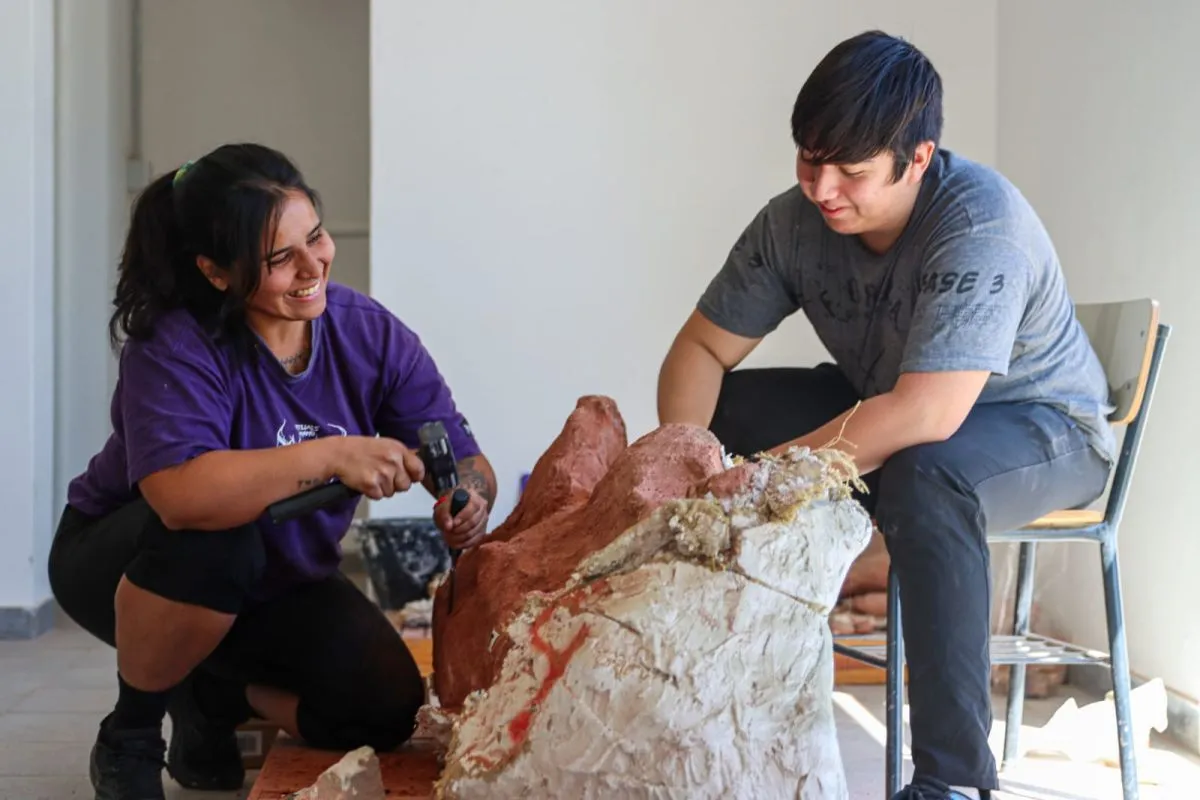 Junto a un estudiante de la UNRN, trabaja sobre el f&oacute;sil de un saur&oacute;podo titanosaurio. Foto: Tania Domenicucci