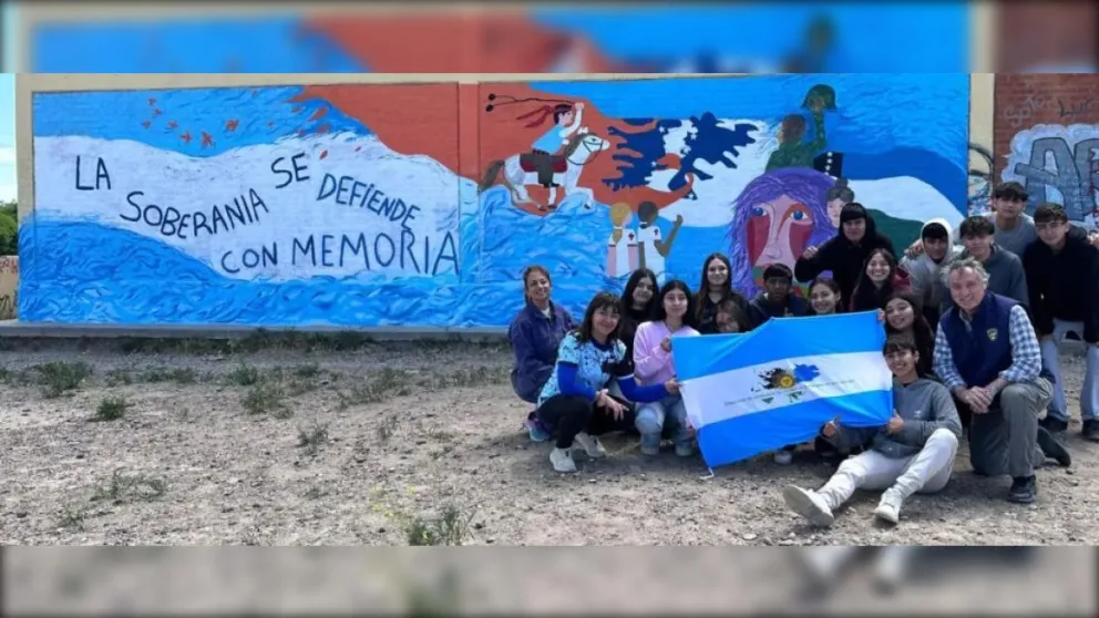 Flores junto a estudiantes secundarios tras la realización de un mural. 